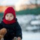 bambino gioca fuori con neve e teddy orsacchiotto