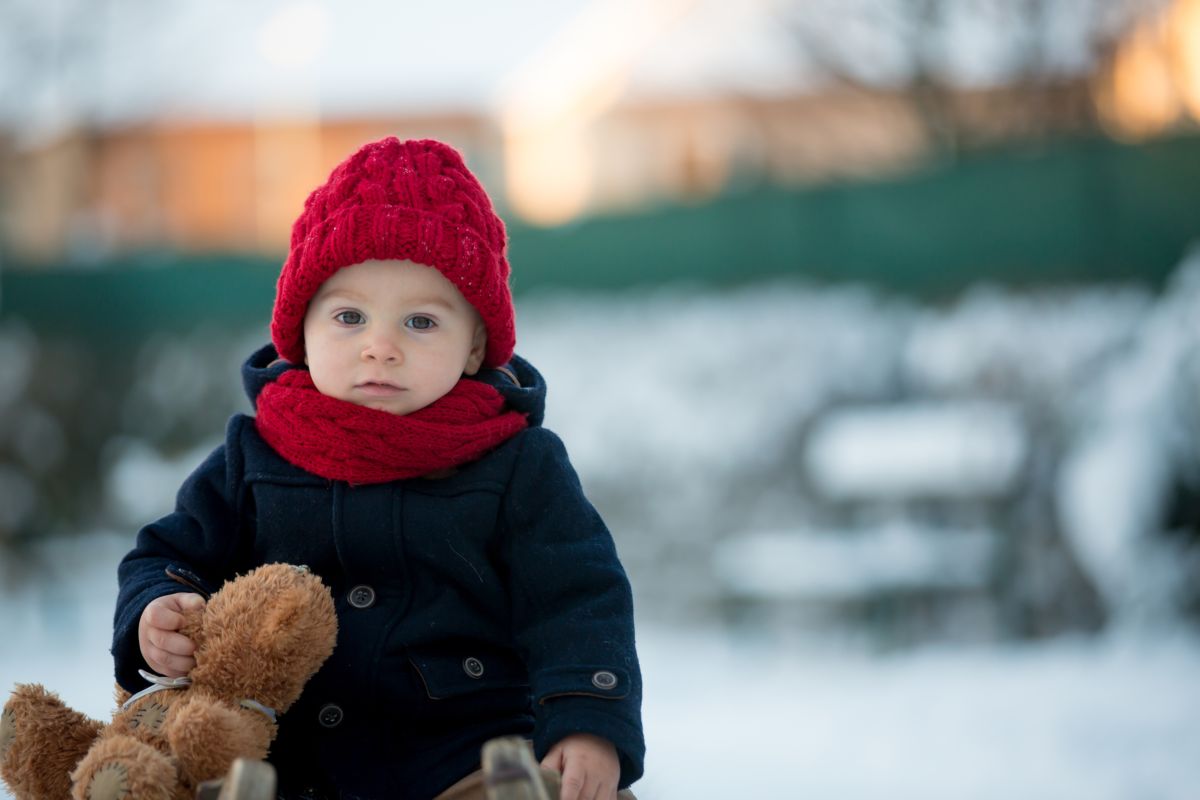 bambino gioca fuori con neve e teddy orsacchiotto