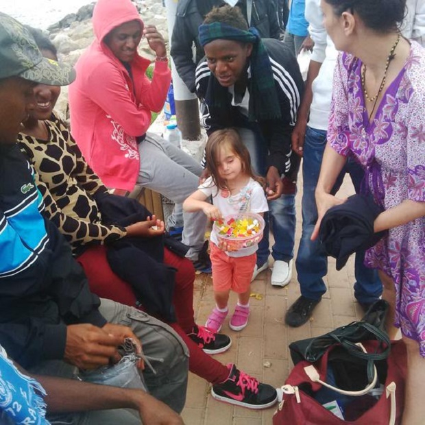 bambina che regala caramelle ai migranti