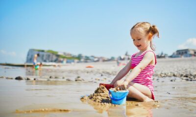 bambina spiaggia giocare con la sabbia