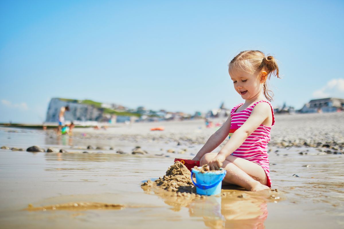 bambina spiaggia giocare con la sabbia