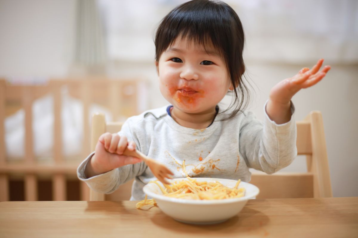 bambina mangia pasta al pomodoro