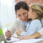 Mamma che lavora al computer con bambina
