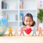 bambina che sorride guardando il mappamondo e tanti manichini uniti, concetto di inclusione