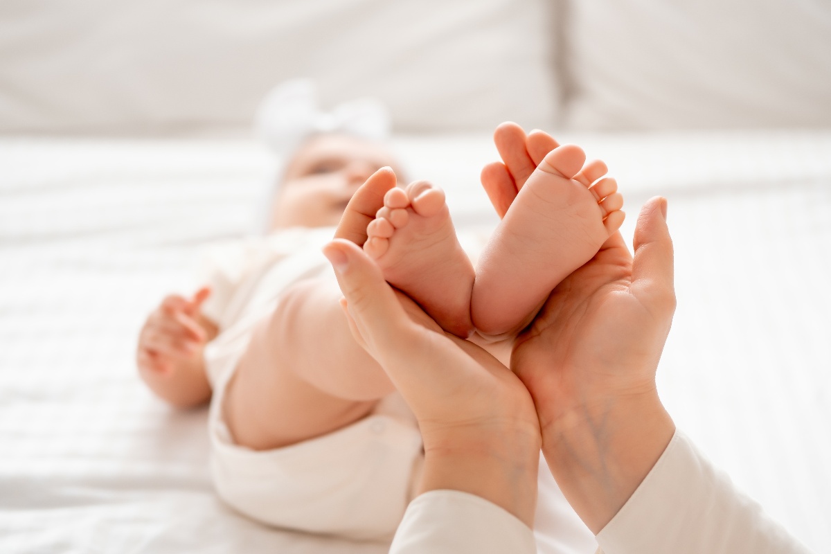 Gesto d'amore: le mani della mamma tengono i piedini del bebè.